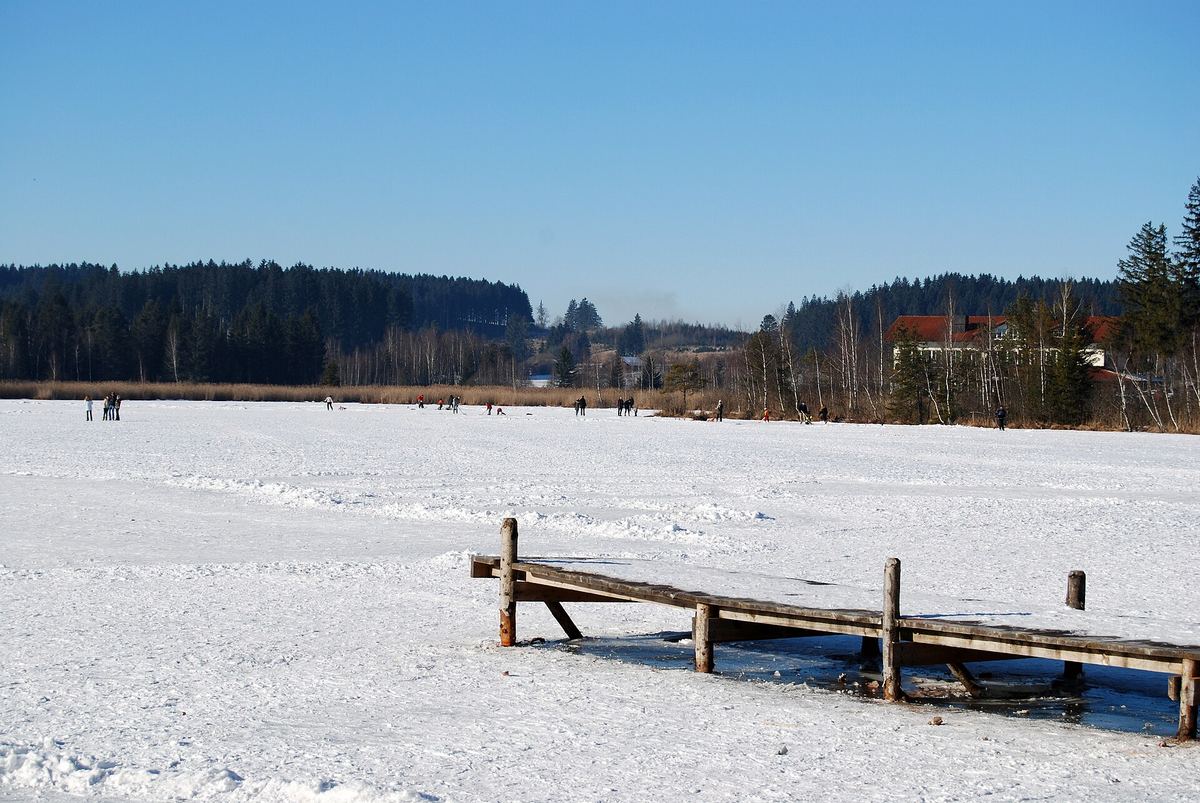 Der zugefrorene Elbsee bei Aitrang mit verschneitem Steg